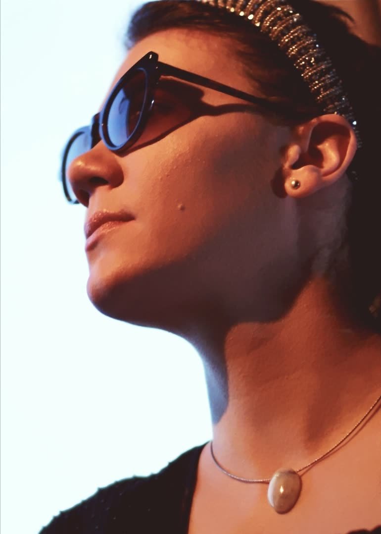 Nahaufnahme im Profil mit Sonnenbrille gegen den hellen Himmel
